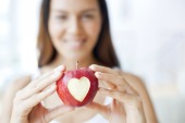 Young woman holding apple with heart